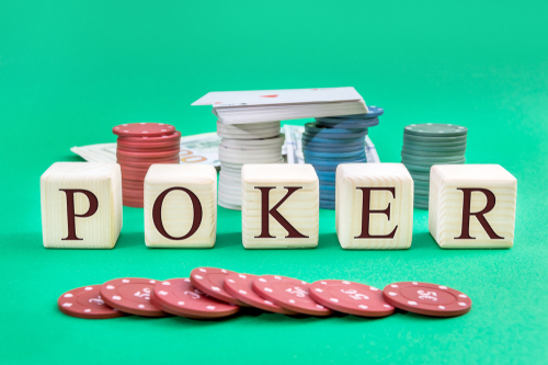 cube de mot écrivant le mot poker, jeton de casino, jeu de cartes et billets de banque posés sur un tapis de jeu